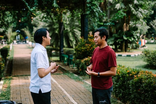 Two Southeast Asian men engaged in a lively conversation at a city square. photo