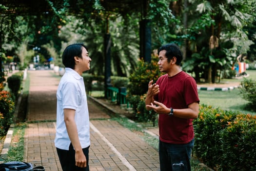 Two Southeast Asian men engaged in a lively conversation at a city square. photo