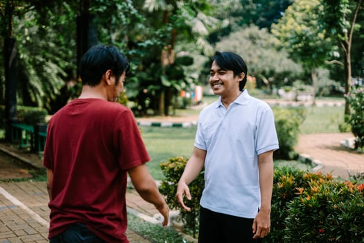 Two Southeast Asian men engaged in a lively conversation at a city square. photo