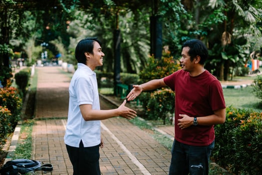 Two Southeast Asian men engaged in a lively conversation at a city square. photo