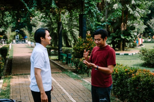 Two Southeast Asian men engaged in a lively conversation at a city square. photo