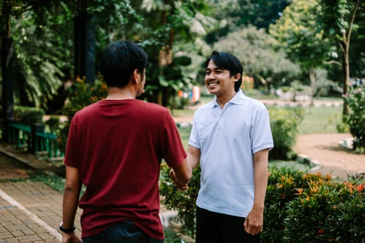 Two Southeast Asian men engaged in a lively conversation at a city square. photo