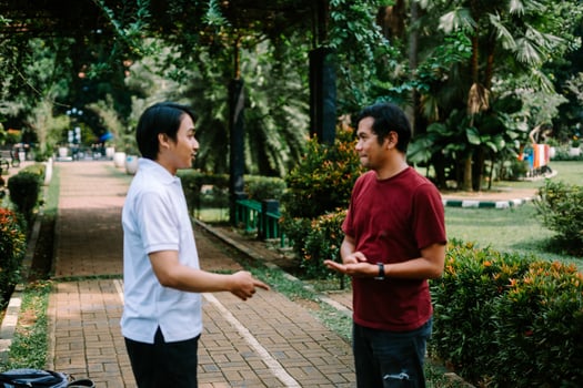 Two Southeast Asian men engaged in a lively conversation at a city square. photo
