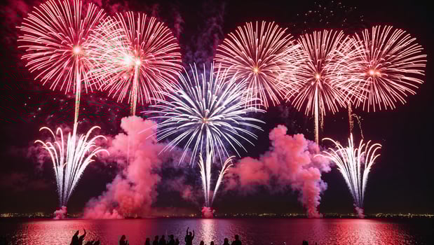 Fireworks over the water with people watching photo