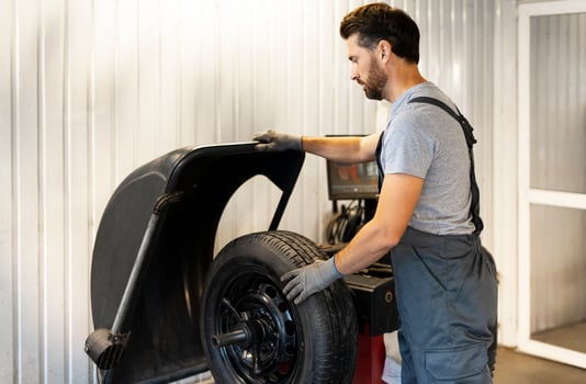 Mechanic mounting a tire on a balancing machine in a workshop photo