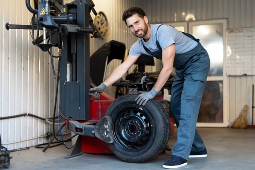 Mechanic changing car tire using professional equipment in a workshop photo