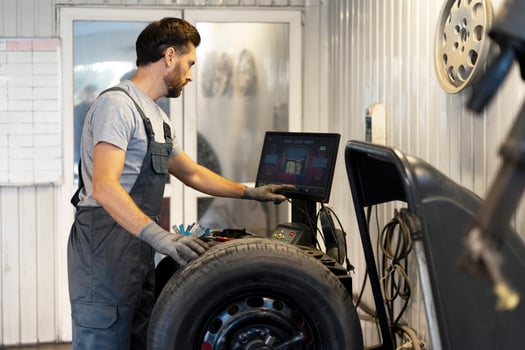 Mechanic using computer balancing machine for car wheel photo