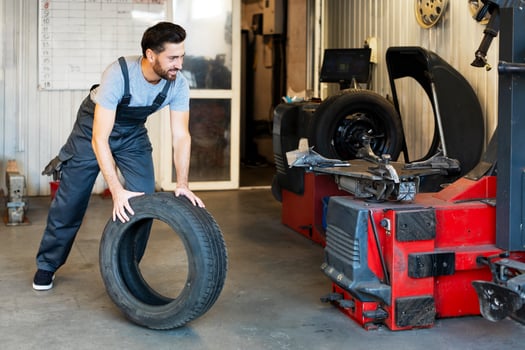 Mechanic lifting tire in a workshop for seasonal change photo