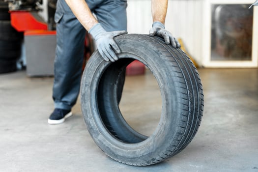 Mechanic holding worn out car tire in repair shop photo