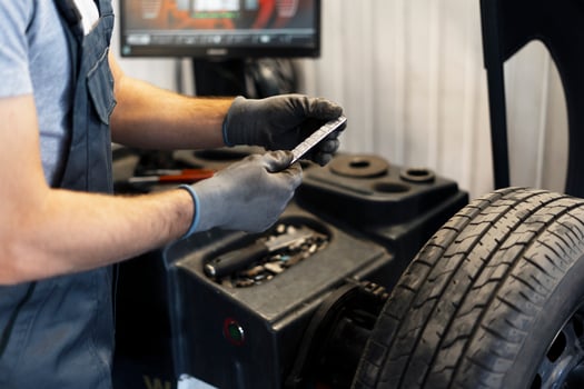 Mechanic holding wheel balancing weight in a garage photo