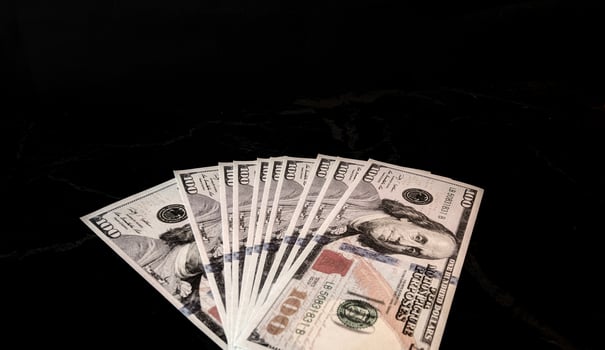 A stack of one hundred dollar bills on a black surface photo