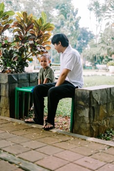 A father and his child sitting and chatting in a city square photo