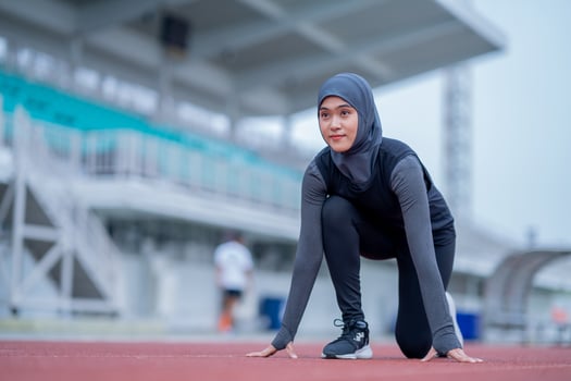 A young asian Muslim woman wearing a black hijab is exercising and running at an outdoor stadium in the morning. Modern Muslim woman concept, Muslim woman sport concept, Islam photo