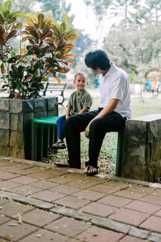 A father and his child sitting and chatting in a city square photo