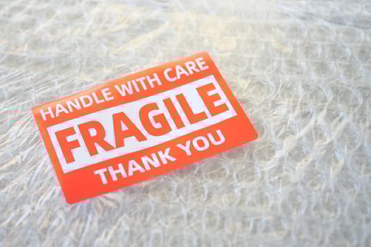 A cardboard box marked with a caution label for fragile goods handling during shipping photo