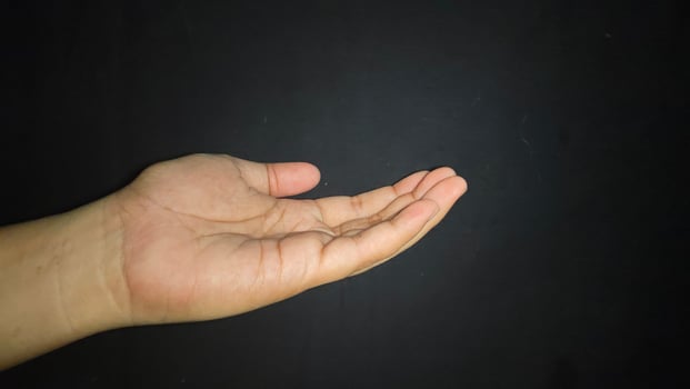 The hand is raised showing a gesture of asking for something. Isolated on black background photo