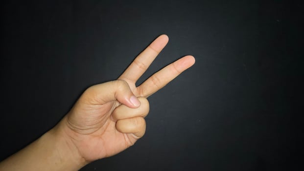 Hand with two fingers up means peace. Isolated on black background photo