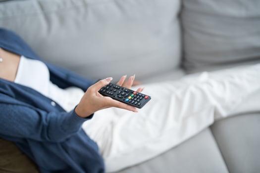 Asian woman Watching smart TV and using remote controller Hand holding television audio remote control at home with the remote control television photo