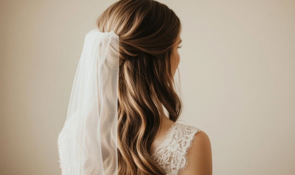 A woman with long brown hair is wearing a white lace veil photo