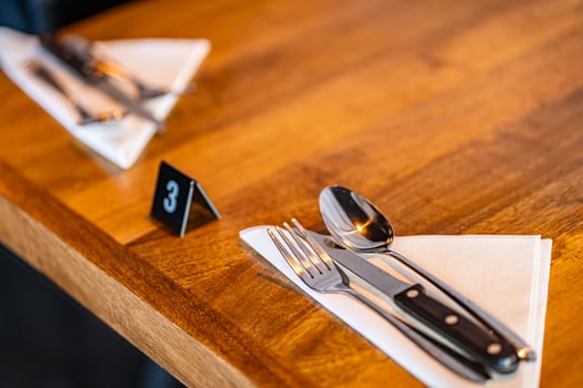 Modern trendy wooden silver appliances - fork and knife on a wooden serving table in the restaurant with a table number photo