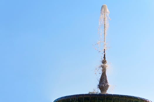 Fountain with shining clear liquid on a sky with clouds background photo