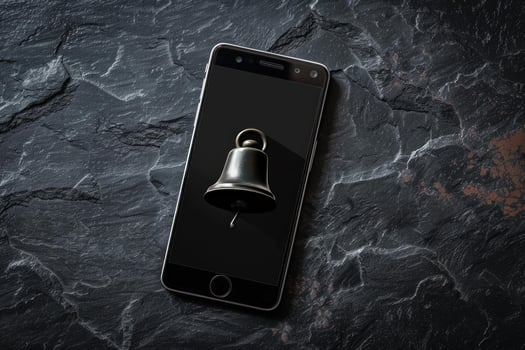 Smartphone showing bell icon on dark slate background photo