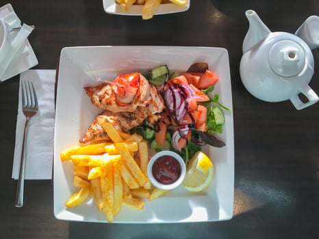 Delicious food - roasted potatoes, chicken breast and fresh vegetables in seaside summer cafe, top view photo