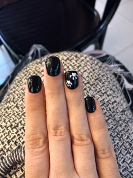 Close-up of a hand with black nail polish and white paw print nail art. photo