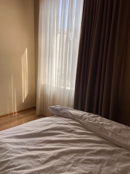 Messy bed with curtain and window view from bed photo