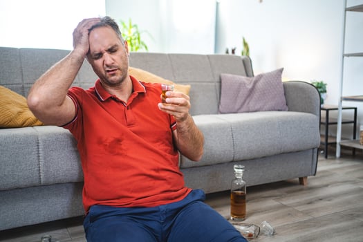 Mature man sitting on the floor and drinking alcohol photo