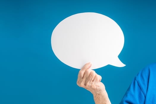 Hand holding of a blank white speech bubble on a blue background photo