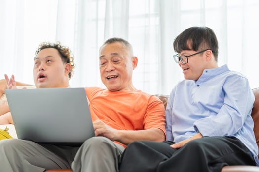 Cheerful grandfather and grandson using laptop doing a call in living room, Senior asian man having a good time sitting on couch at home with adult son photo