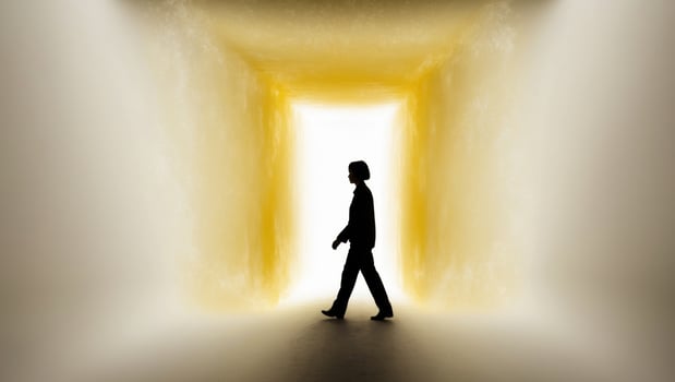 A man walking through a tunnel with light coming from the end photo