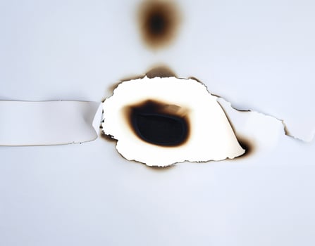 A burnt hole in white paper with singed edges, offering a unique texture for design elements or backgrounds. photo