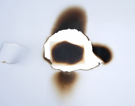 A burnt hole in white paper with singed edges, offering a unique texture for design elements or backgrounds. photo