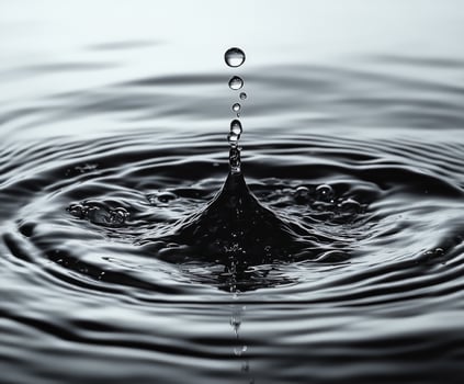 Water droplet falling creating concentric ripples on water surface photo