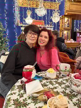 Mother and daughter sit together at a festively Christmas decorated table, surrounded by holiday lights and ornaments in cozy cafe. Enjoying warm drinks, showcasing a joyful and celebratory atmosphere photo