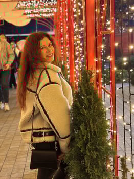 Millennial woman smiles brightly as she stands in a festive Christmas setting adorned with twinkling lights. the warm glow of the decorations creates a joyful and cozy holiday winter atmosphere photo