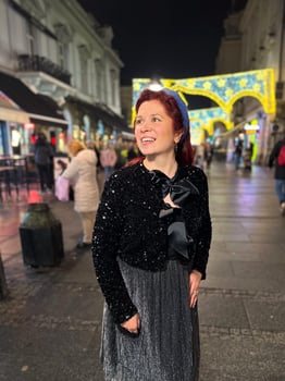 Millennial woman standing outdoors at Christmas night,. City lights in the background create a warm and Christmas holidays atmosphere, enhancing the peaceful and confident expression on her face photo