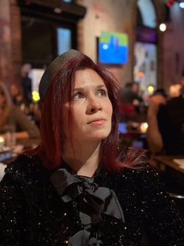 Millennial woman in a sequined outfit sits thoughtfully at a dimly lit cafe. the festive ambiance with hanging decorations adds a warm, celebratory vibe to the scene. photo