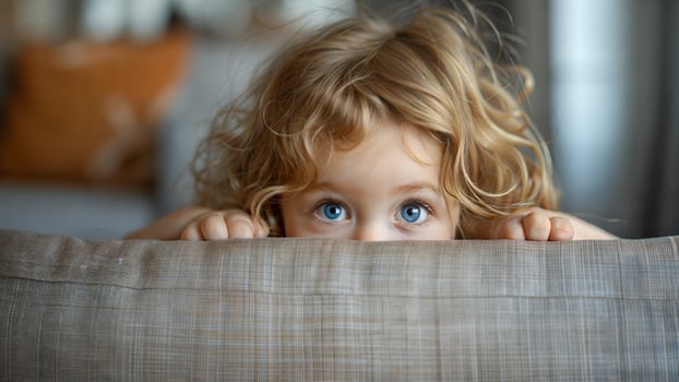 A young child peeking over the edge of a couch photo