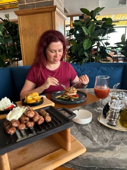 Millennial woman enjoys a beautifully prepared meal in a cozy restaurant setting, engaging in a delightful dining experience surrounded by greenery. Inviting atmosphere emphasizes comfort photo