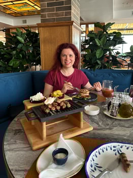 Millennial woman enjoys a beautifully prepared meal in a cozy restaurant setting, engaging in a delightful dining experience surrounded by greenery. Inviting atmosphere emphasizes photo