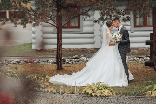 A bride and groom are standing in front of a house photo