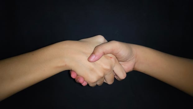 Hands shaking between a man and a woman. Isolated on black background photo