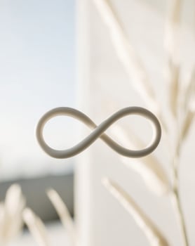 A white infinity symbol is sitting on a window sill photo