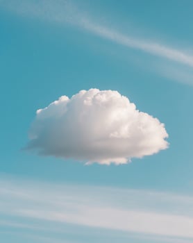 A cloud is floating in the sky above a field photo