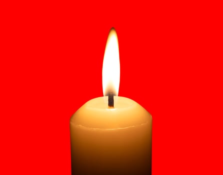 A single burning candle flame or light glowing on a big white candle isolated on red background with clipping path photo
