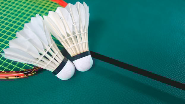 White badminton shuttlecocks and badminton rackets on green floor indoor badminton court. Concept for badminton competition and its lovers. photo