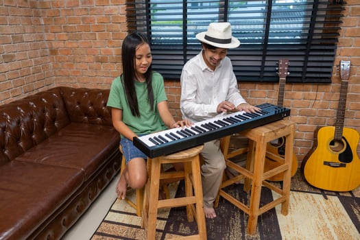 Young asian girl is learning how to play keyboard from her teacher in the after school music class for education children skill and talent development concept photo
